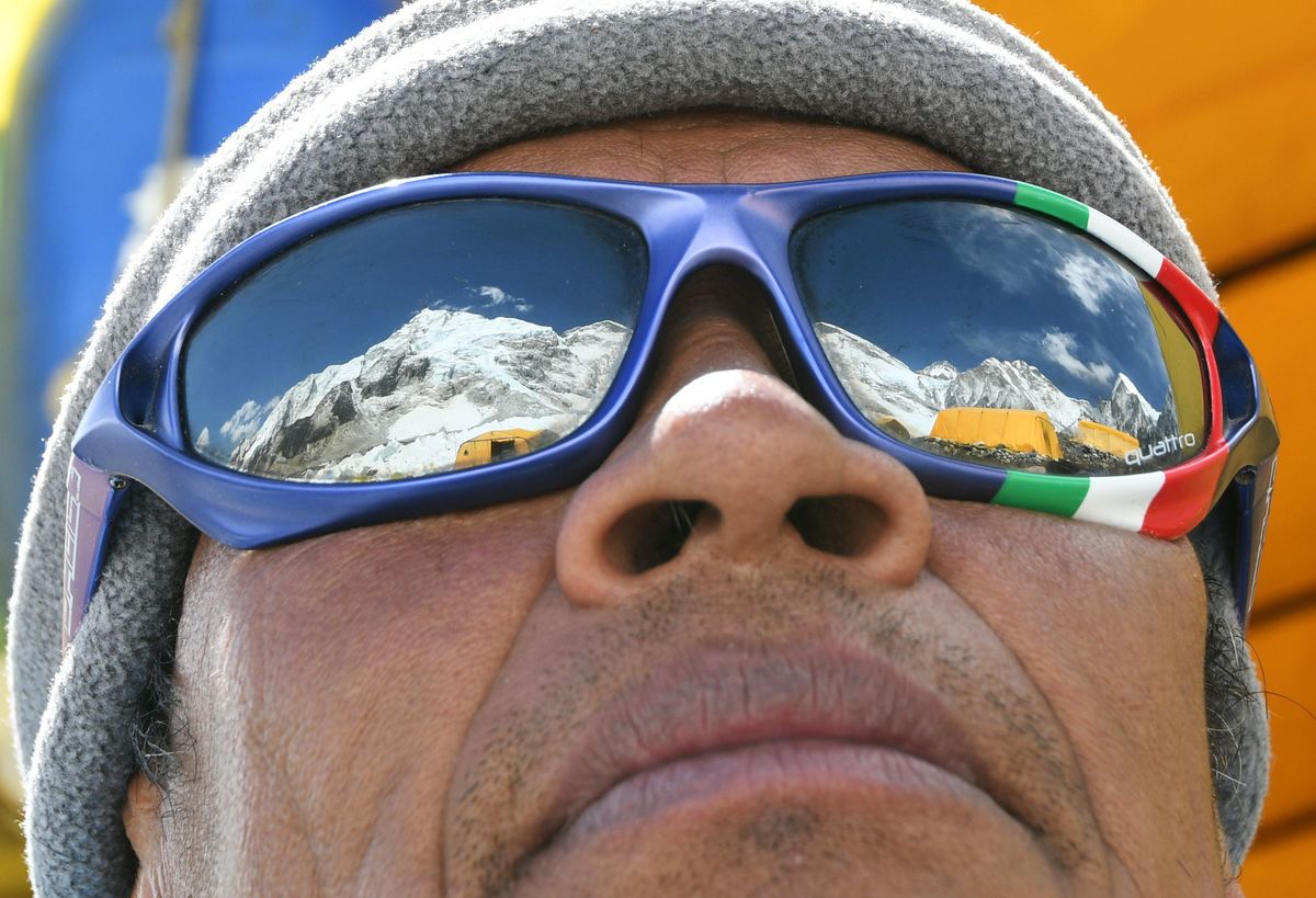 Mount Everest is reflected in a man's sunglasses