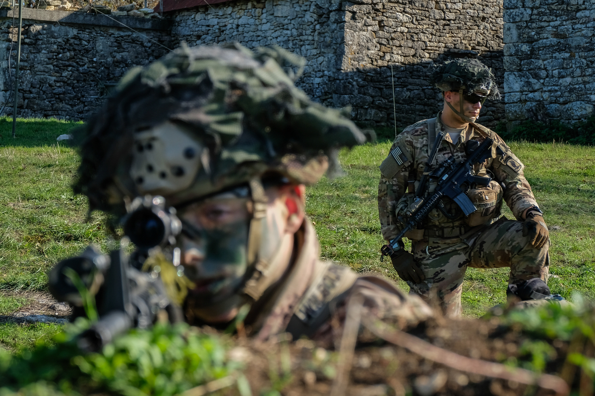 a man aiming in the scope of his weapon during military training