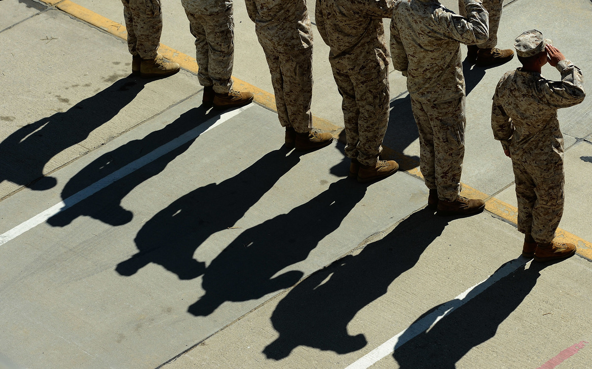 Members of the US military salute during planeside honors for US Army Ranger Sgt. Thomas R. MacPherson