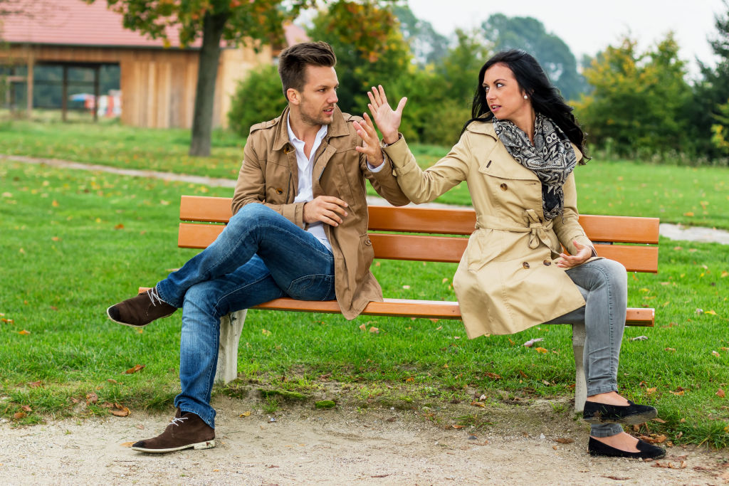 man and woman sitting on a bench in an argument