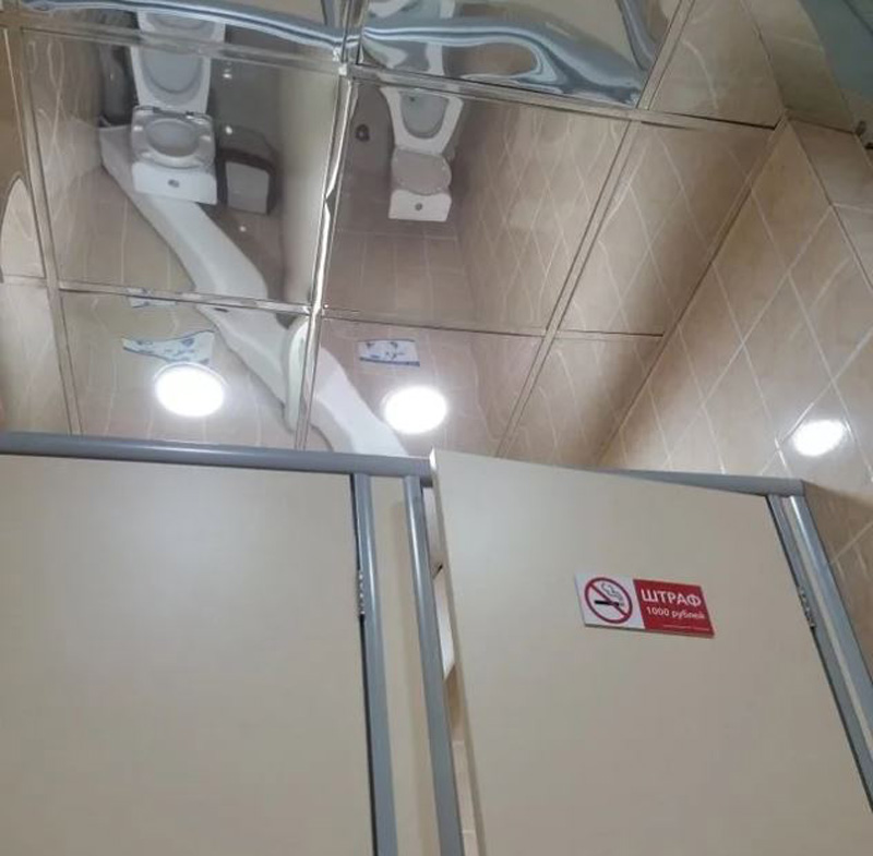 bathroom with mirrored ceiling allowing you to see whoever is in the stall