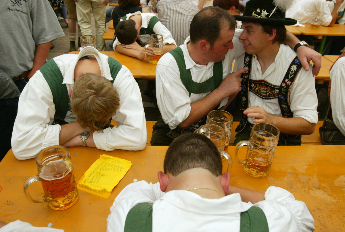 Two drunken men in traditional Bavarian outfits converse beside their passed out comrades at the annual Oktoberfest celebration September 21, 2003 in Munich, Germany.
