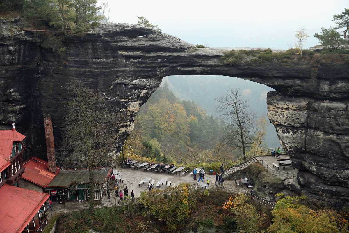 Visitors hike under the Pravcicka Brana natural stone bridge in an area known as Czech Switzerland