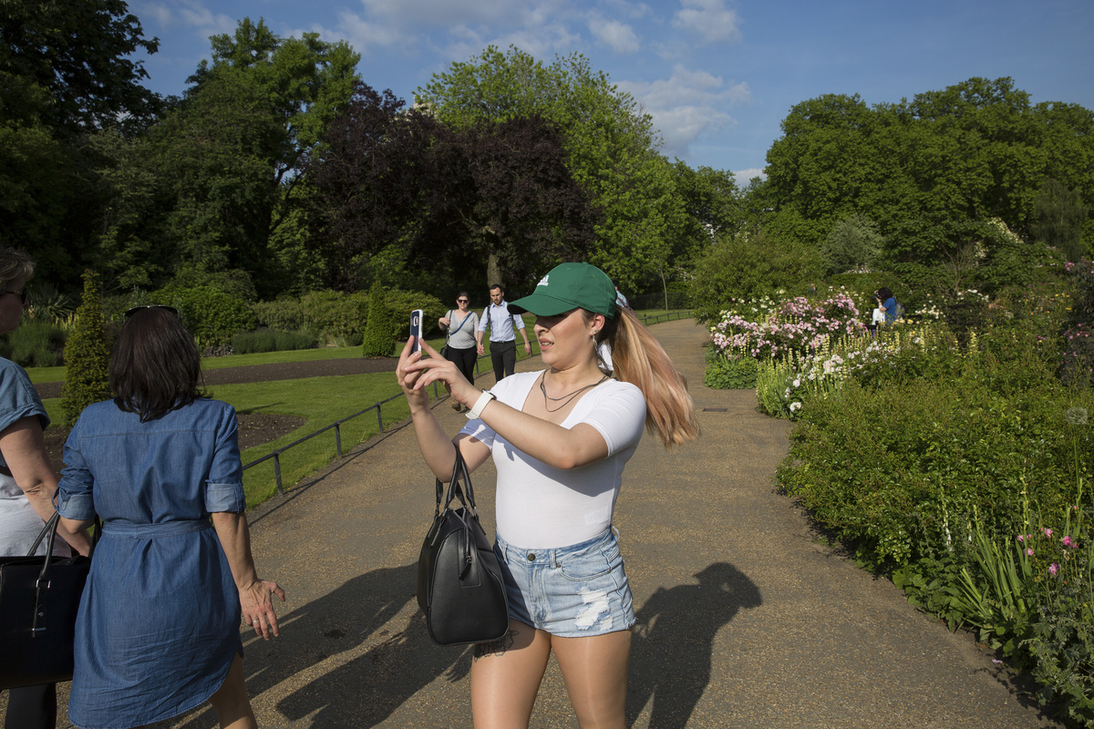 A girl takes photos on her mobiles phone in Hyde Park wild gardens on 24th May 2017 in London, United Kingdom.