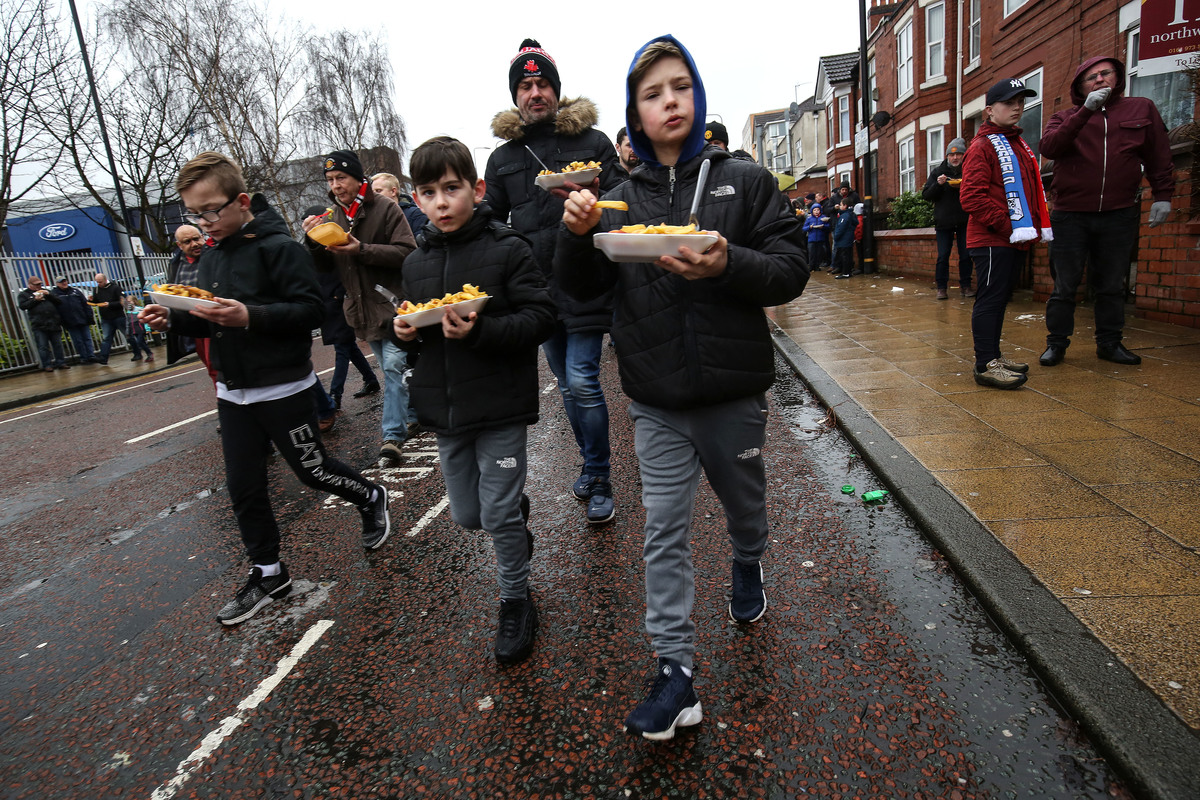 Fans walk to the match eating chips during the Premier League match between Manchester United and Huddersfield Town at Old Trafford on February 3, 2018 in Manchester, England.
