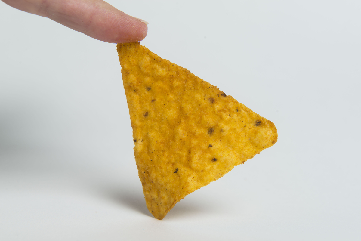 finger holding up a dorito