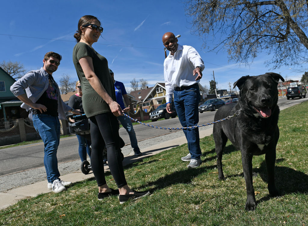 Neighbors admire a black, leashed dog