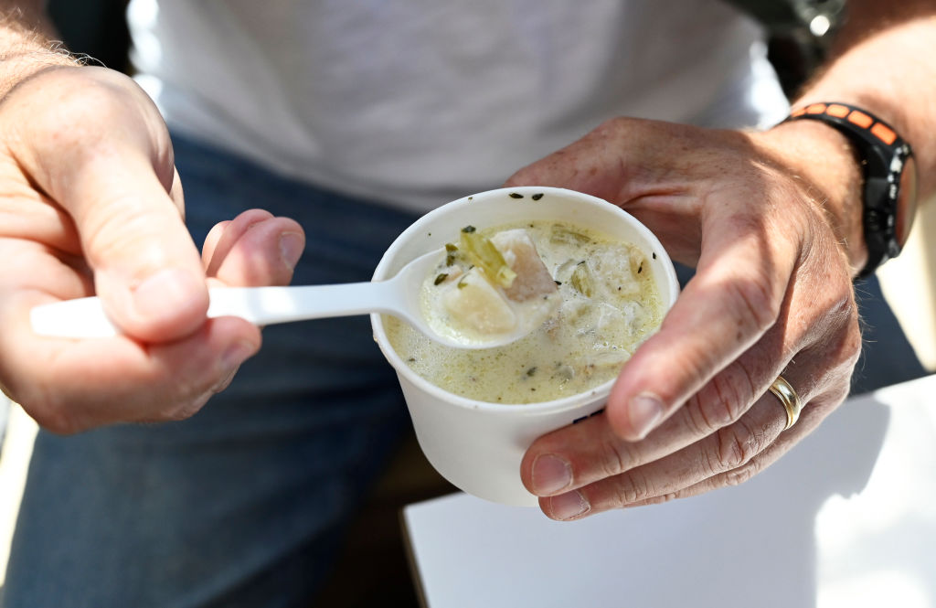 A man spoons a cup of clam chowder