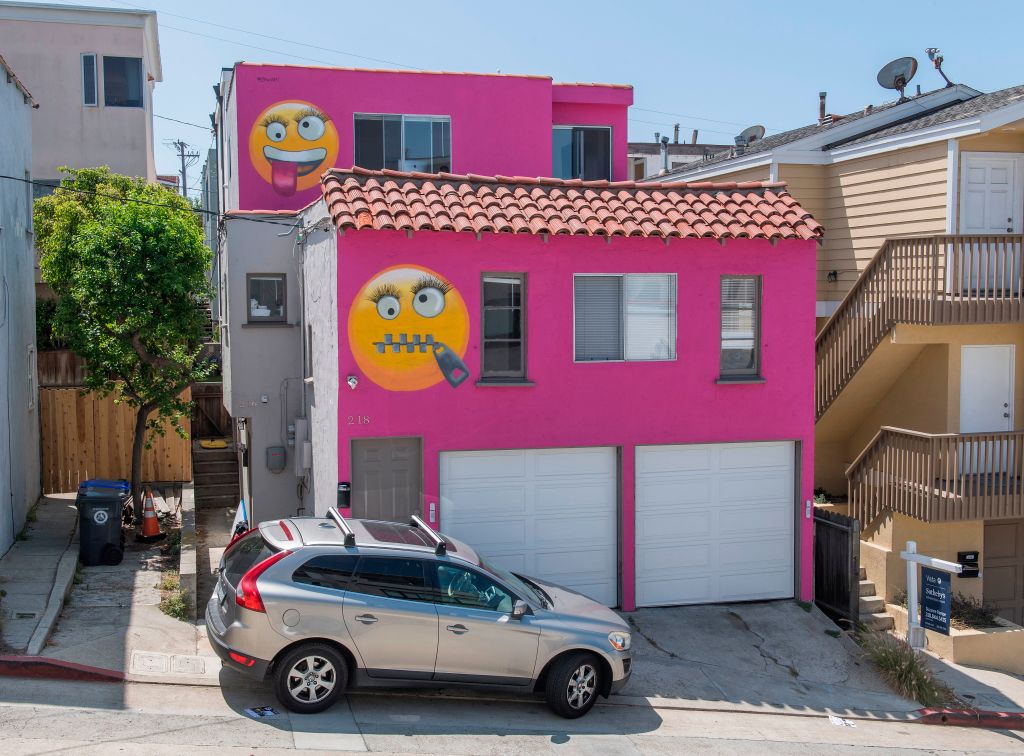 A hot pink house with emogis painted on