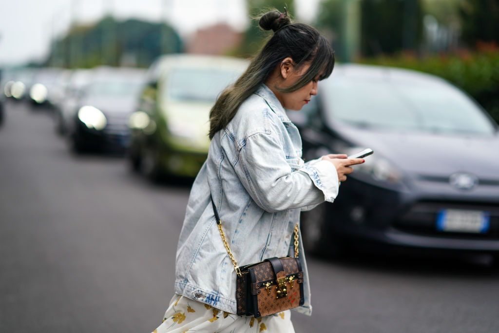 A woman texts while crossing the street