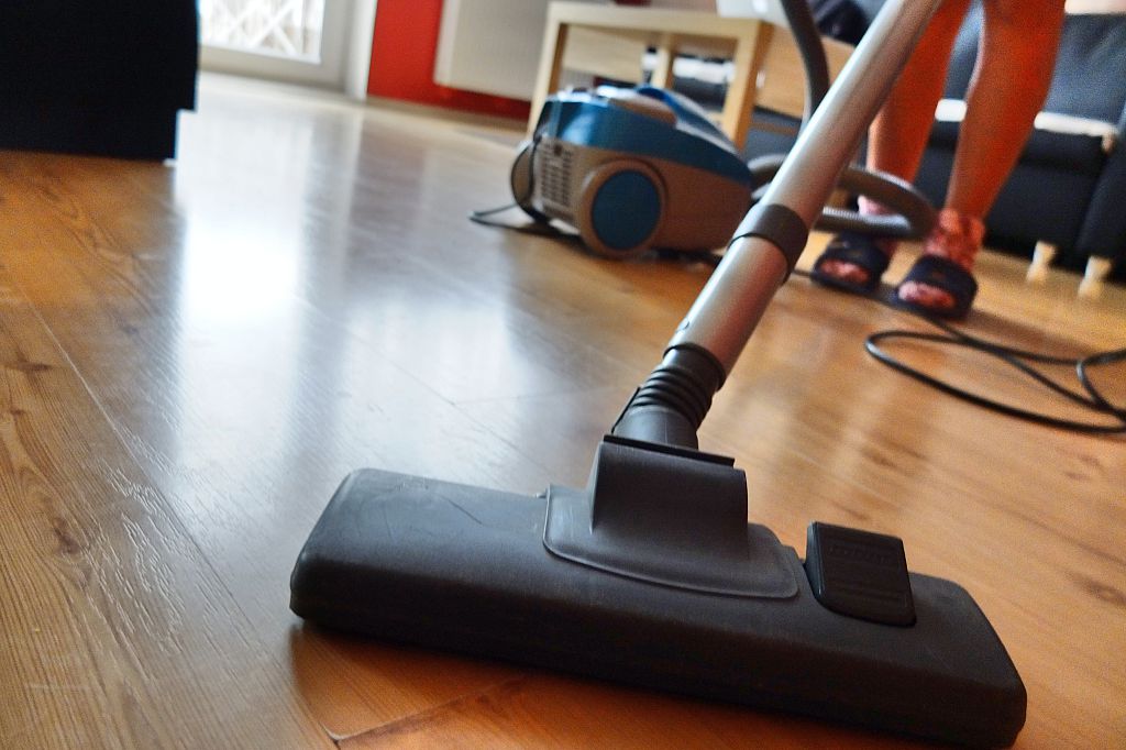 A woman vaccums hardwood floors