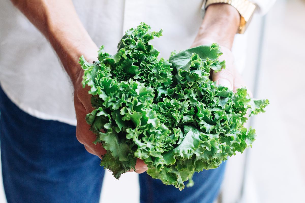 Man holds a bundle of kale