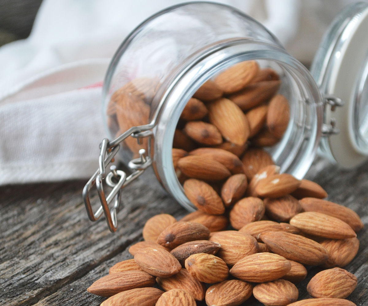 Fresh almonds pour out of a small glass jar