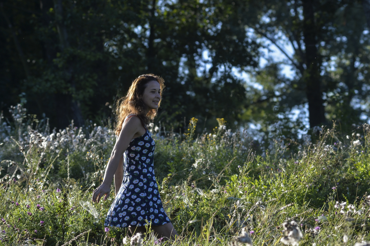 Young woman walking in the field on early summer morning in...