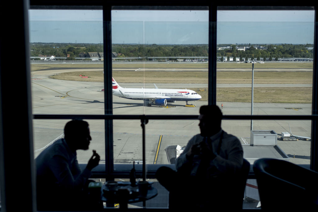 The Silhouette Of Men Talking In An Airport Window