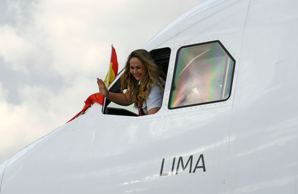 A Female Pilot Waves Out An Airplane Window