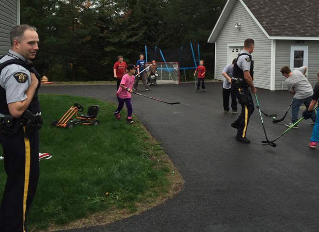 Police Officers play road hockey with children