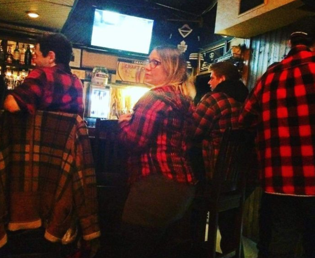 All people in small town bar are wearing red plaid flannels