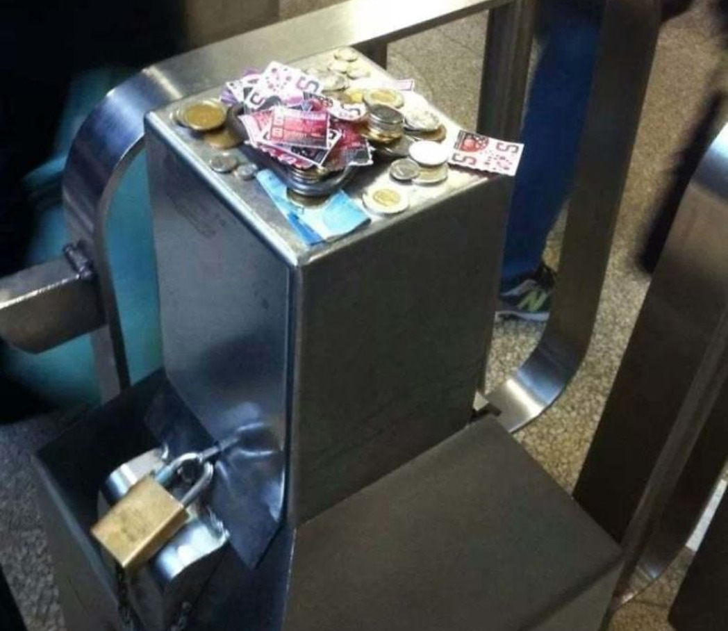 Subway tickets and change on top of a broken subway gate