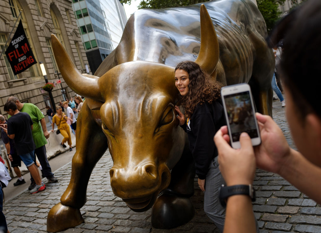 Tourists pose with the Wall Street bull statue