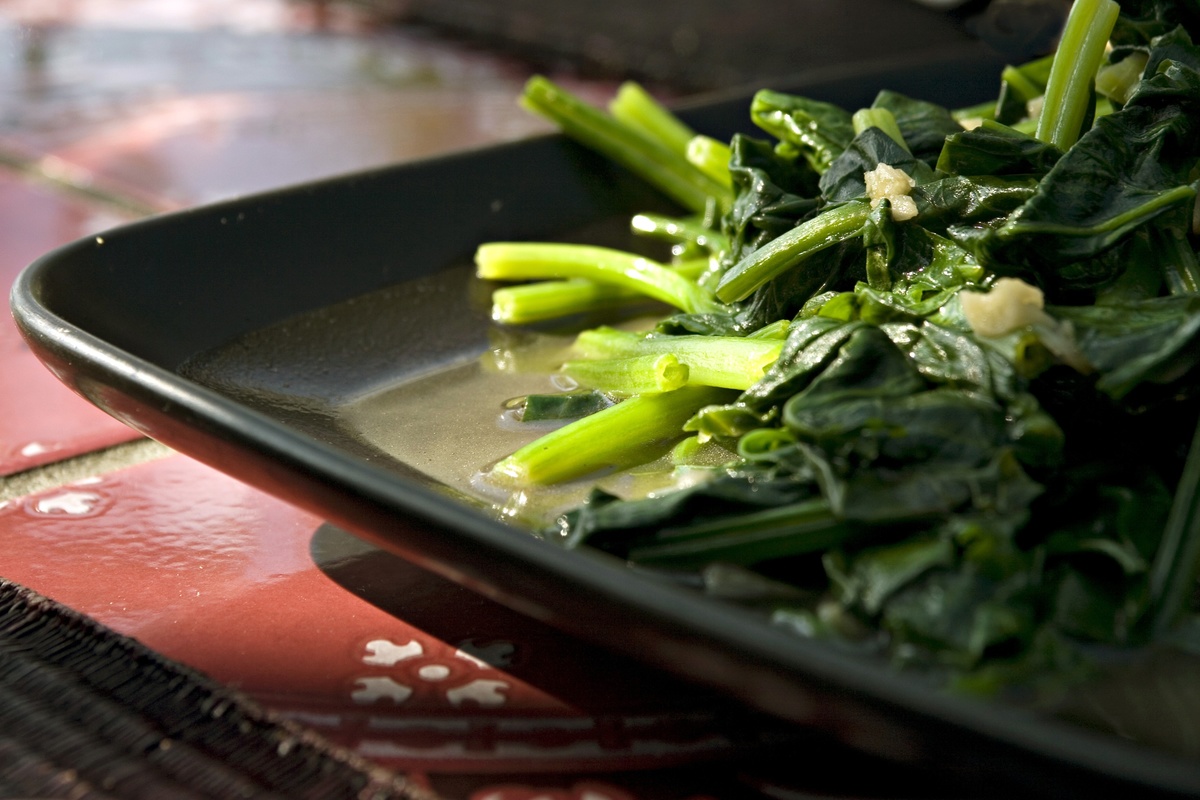 Freshly cooked chinese spinach sits on a pan.
