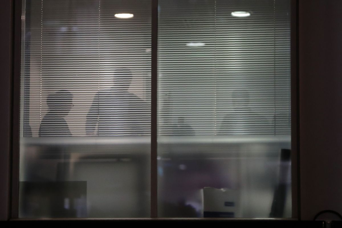 The silhouettes of people are seen through blinds inside the offices of Cambridge Analytica.