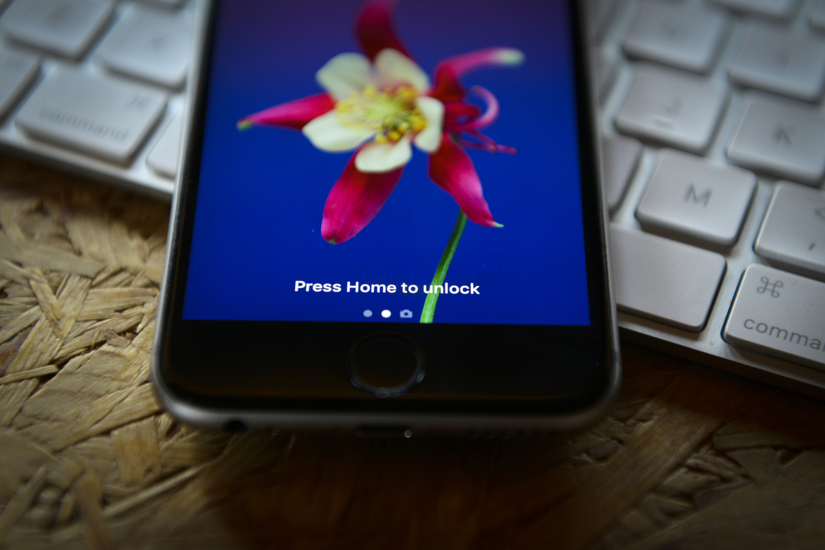 An unlock message is seen on an iPhone on top of a Macbook computer.