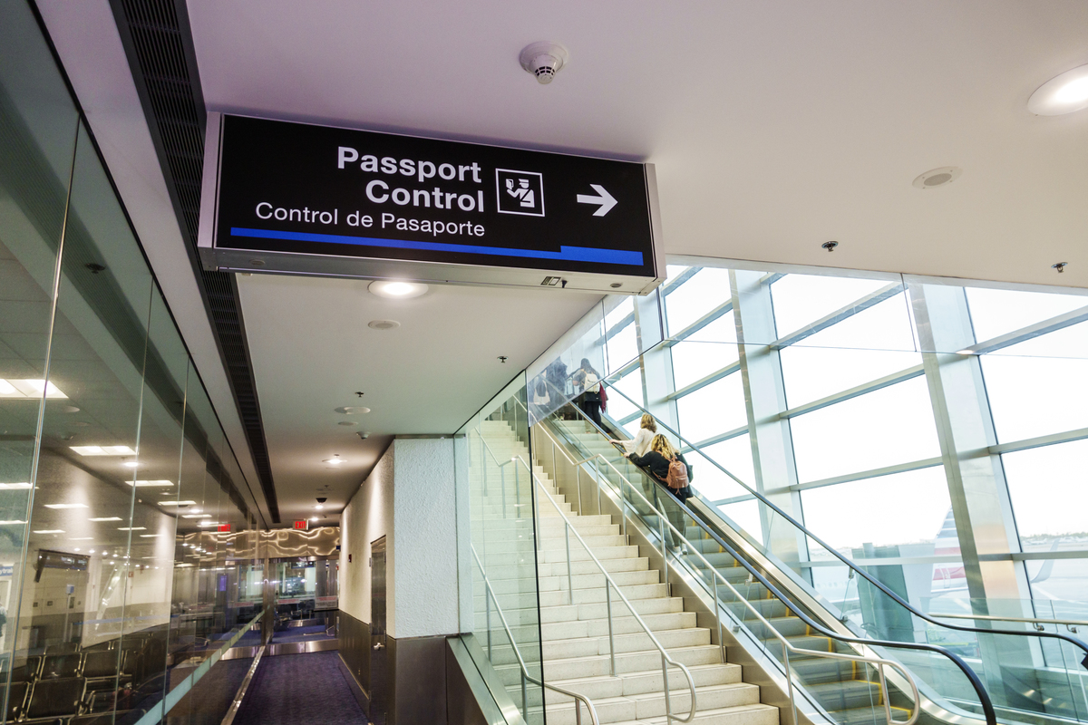 Bilingual passport control sign points to passport approval in a Miami International Airport.