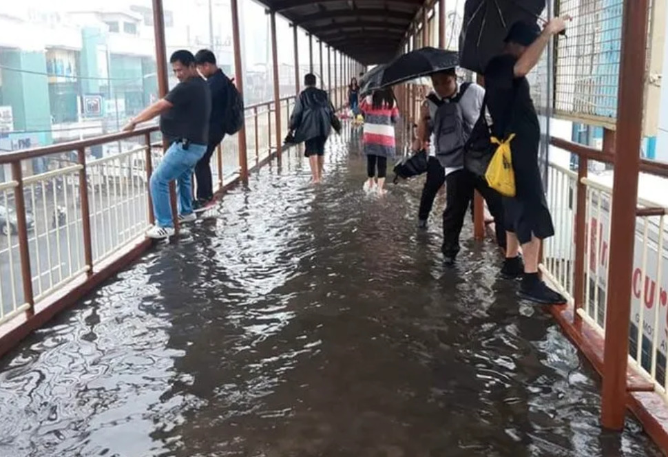 flooded bridge as people trying to walk on edge railings