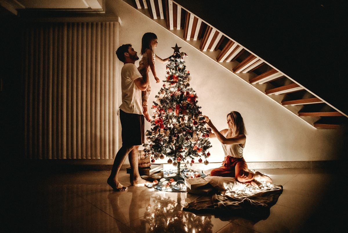family hanging lights on christmas tree