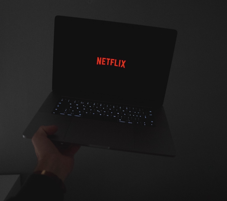 someone holding up a computer that is streaming Netflix