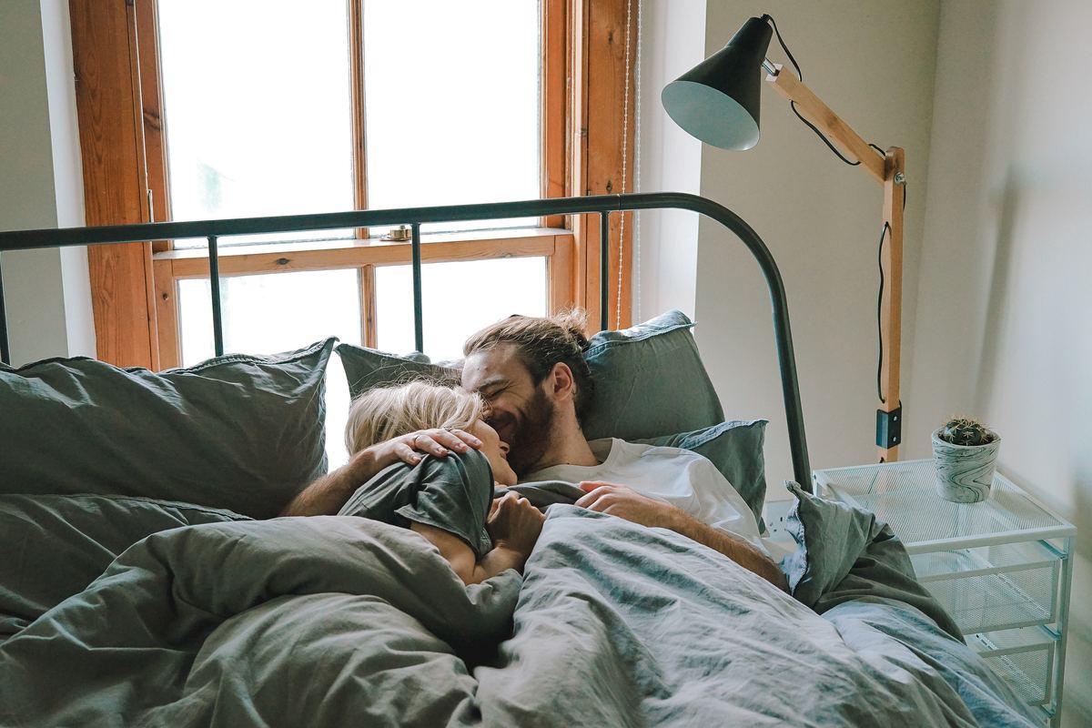 man pressing face into girl's hair in bed