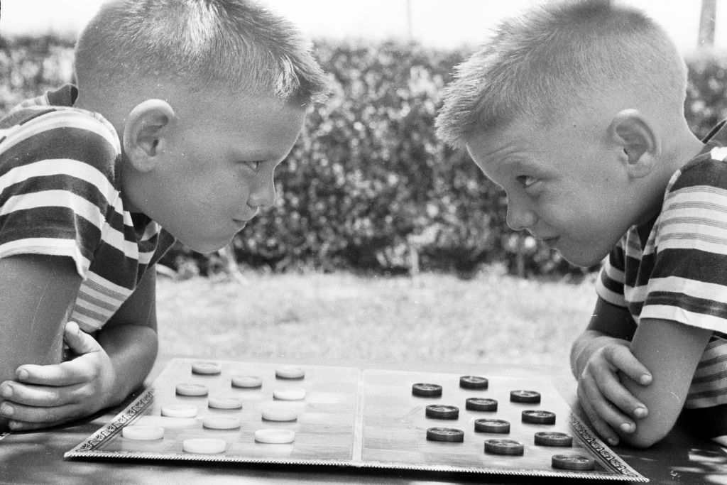 circa 1955: Identical twins Bobby and Jerry psych up for a game of checkers