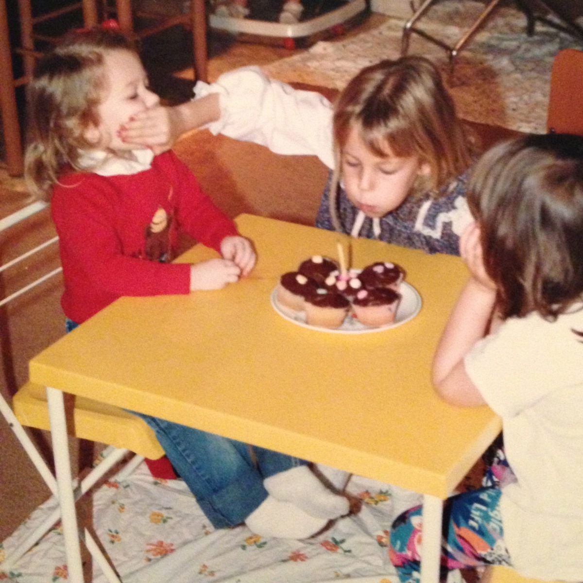 girl stopping sibling from blowing out her birthday cake