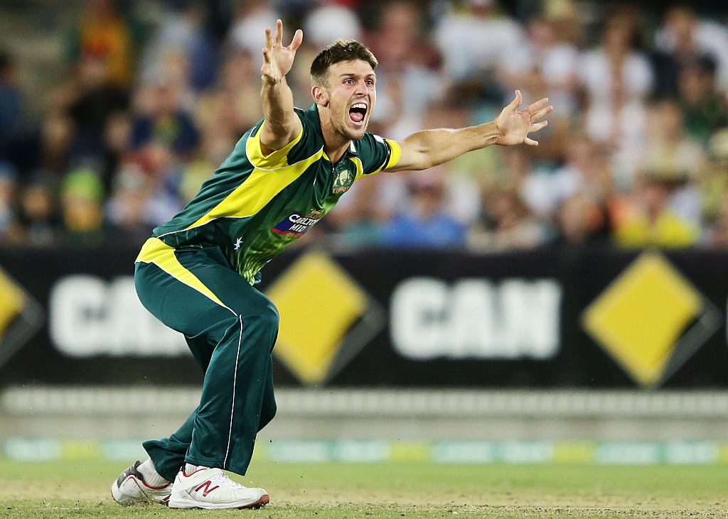 An athelete holds his arms out on the field and yells.