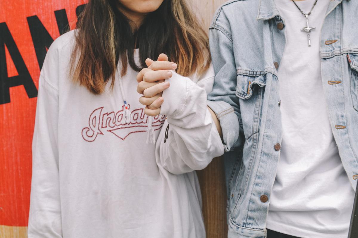 man and woman holding hands in front of wall