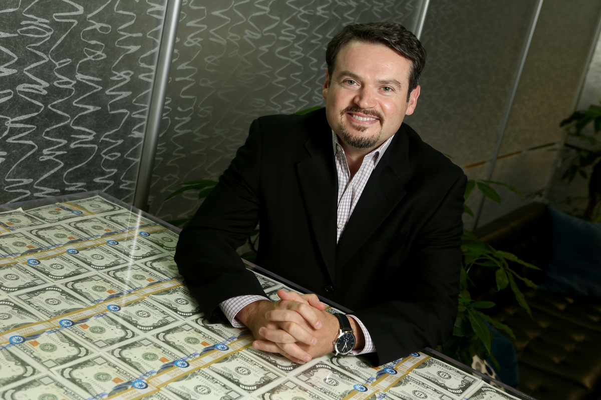 Coupa CEO Rob Bernshteyn poses for a photograph, with stacks of oversized, mock $1000 bills