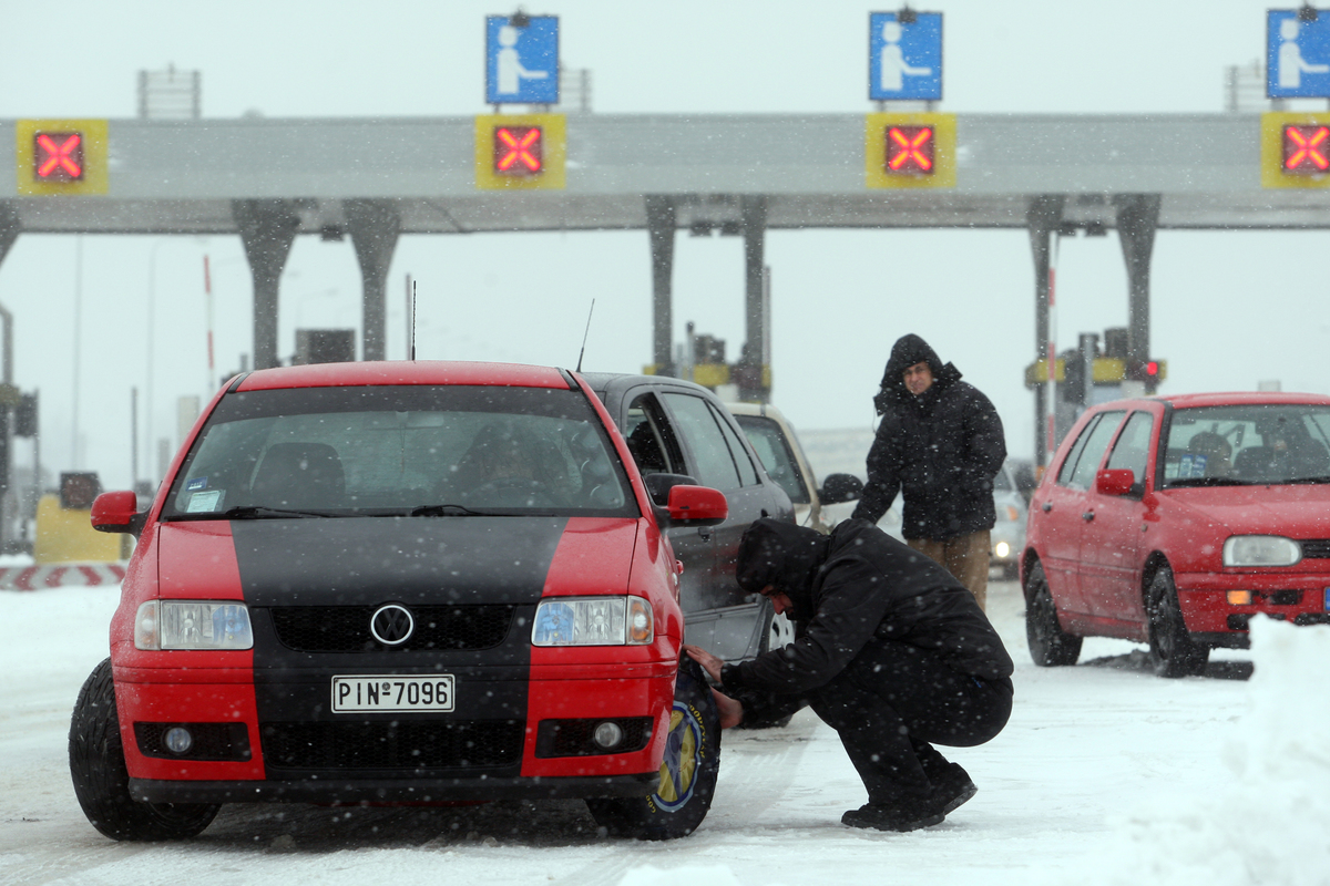 Drivers put snow chains to their cars 