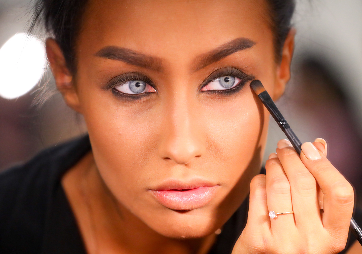 A woman applies black eyeshadow.