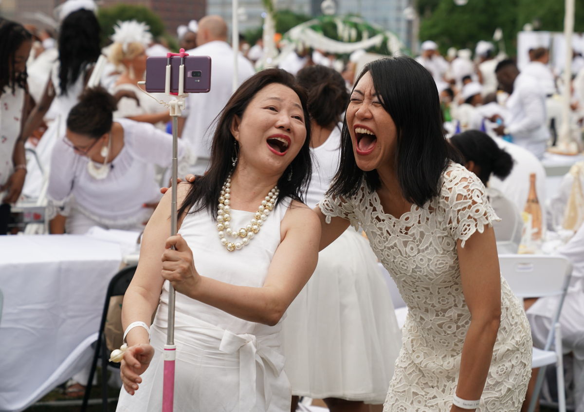 Women laugh together as they take a selfie.