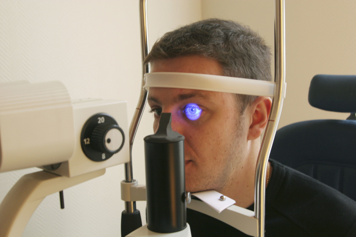 An Optician exams eyes with an ultraviolet lamp.