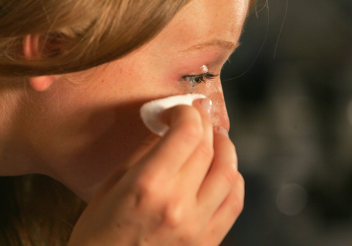 A model cleans makeup off her eyes.