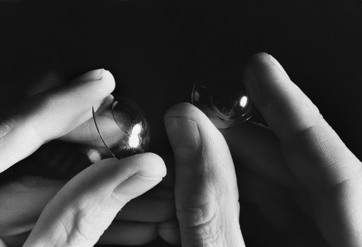 A person holds a pair of contact lenses.
