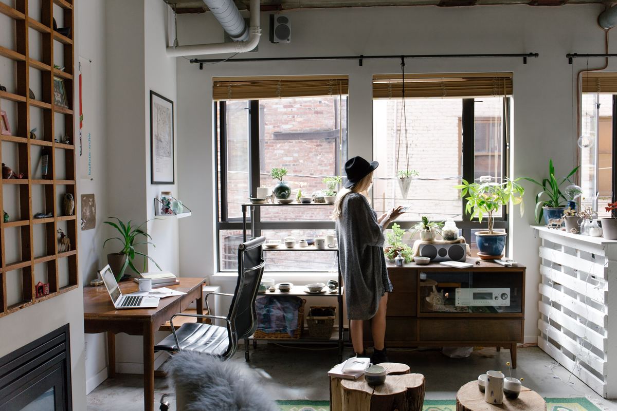 woman looking out window of apartment by herself