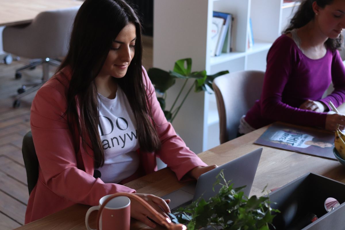 woman working at laptop next to another woman
