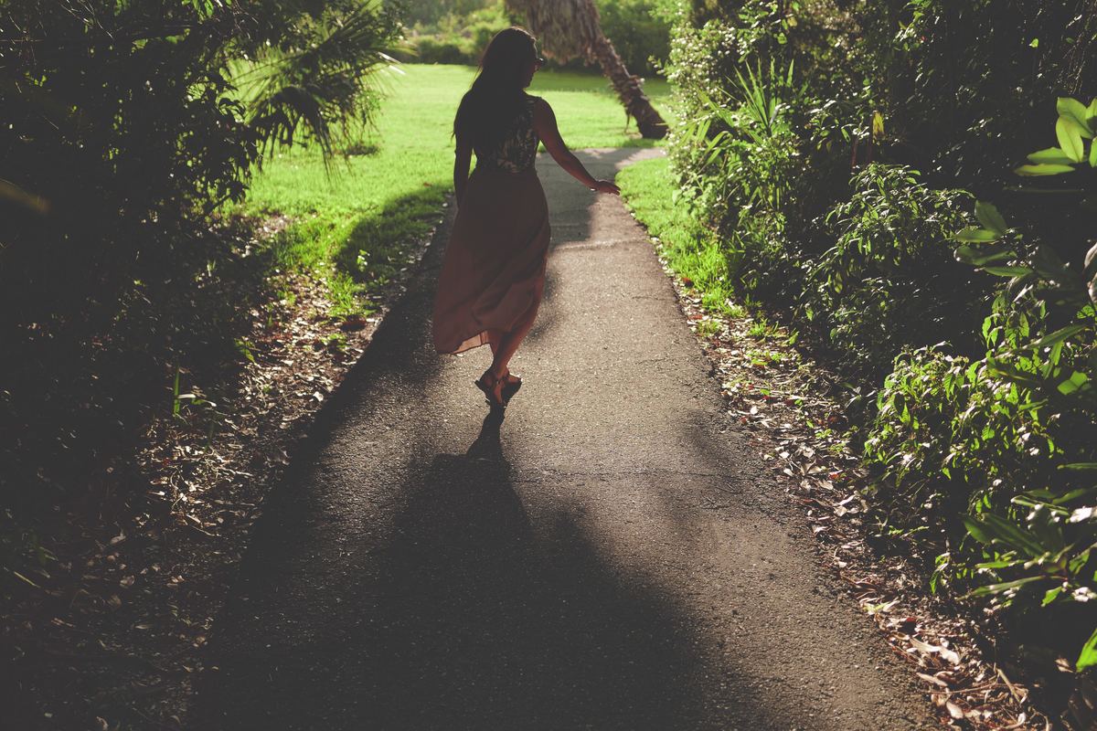 girl in pink dress walking through garden pathway