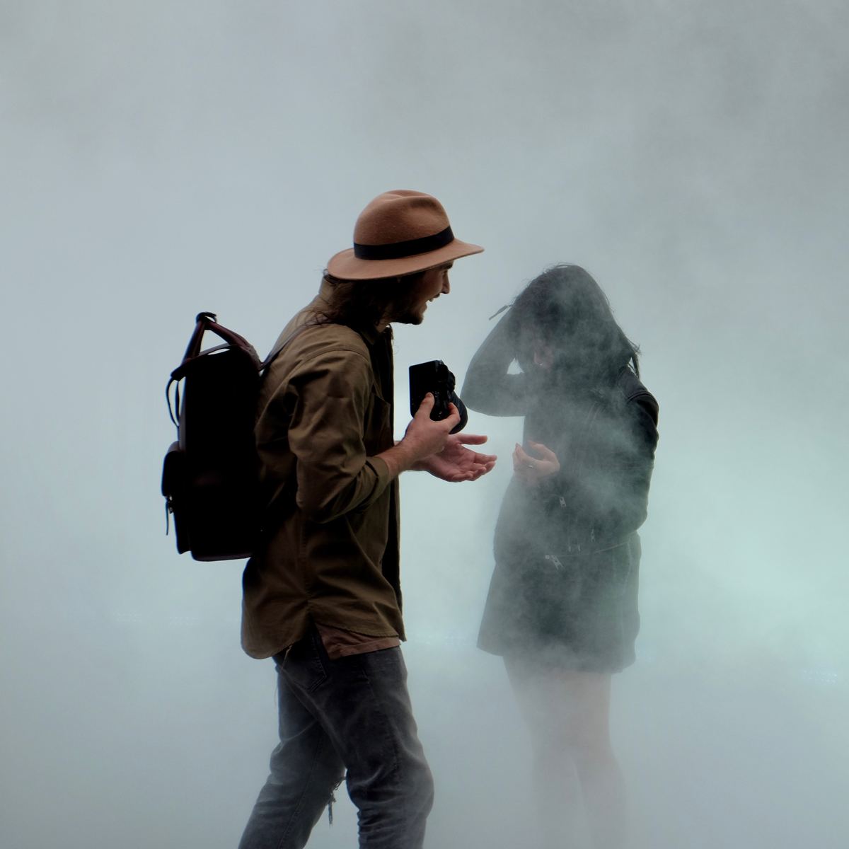 man holding camera with woman in foggy weather