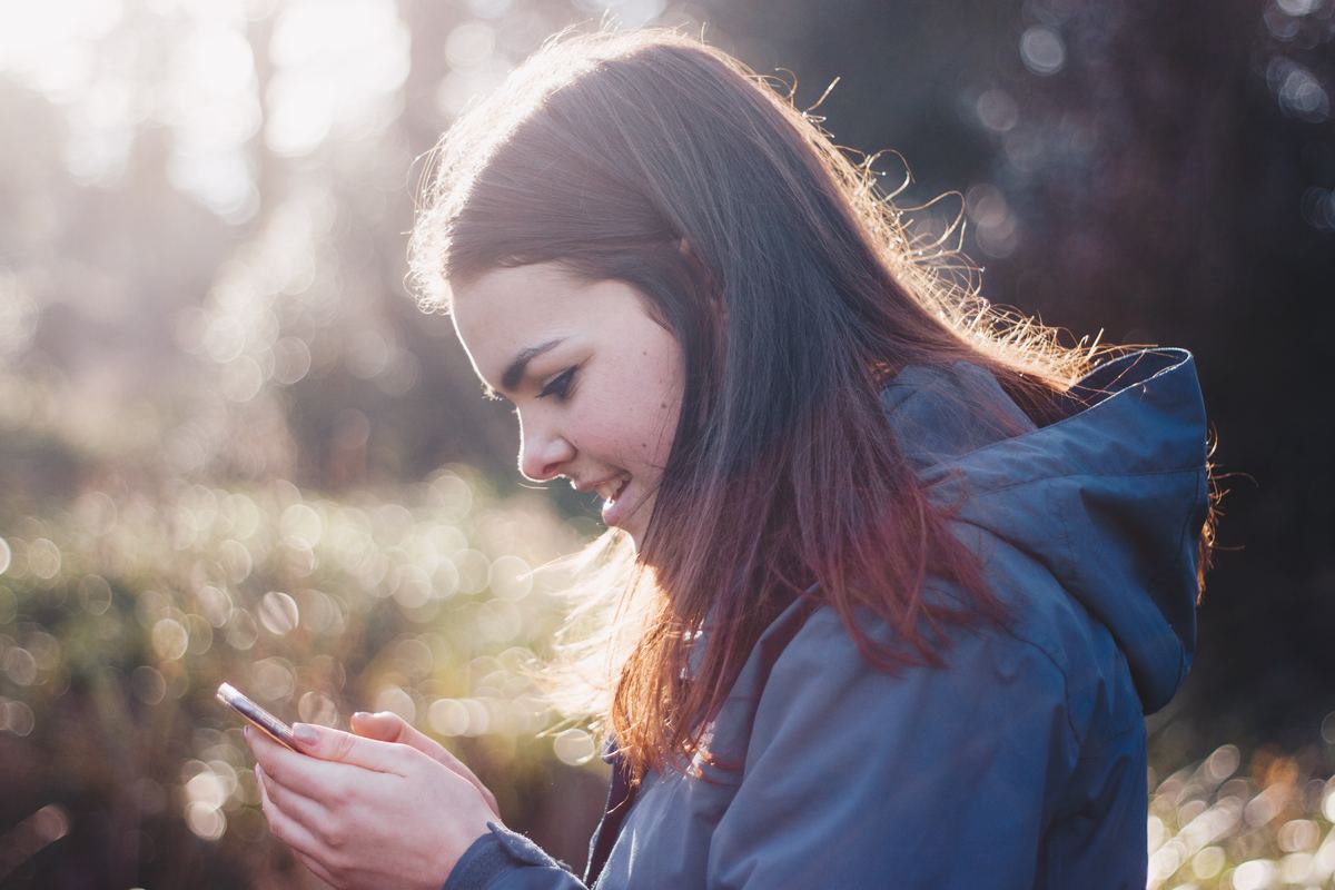 girl standing outside looking at phone