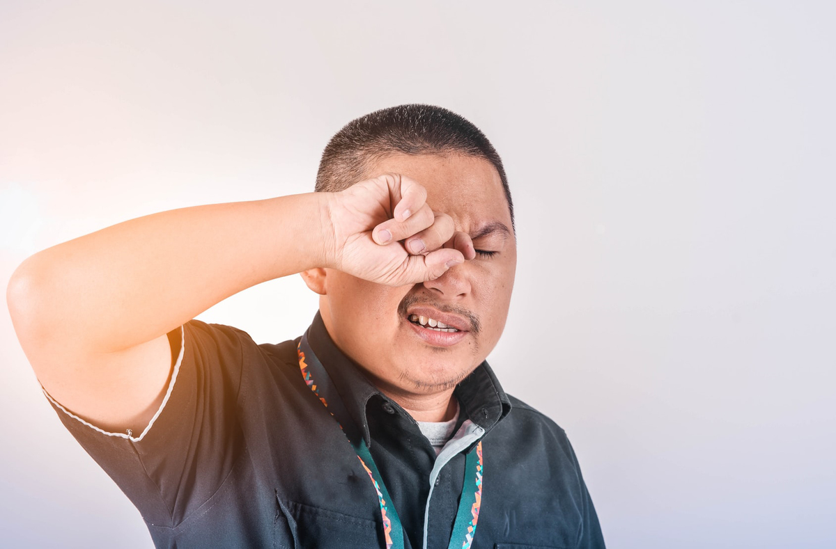 A man rubs his eyes to assuage an itch.