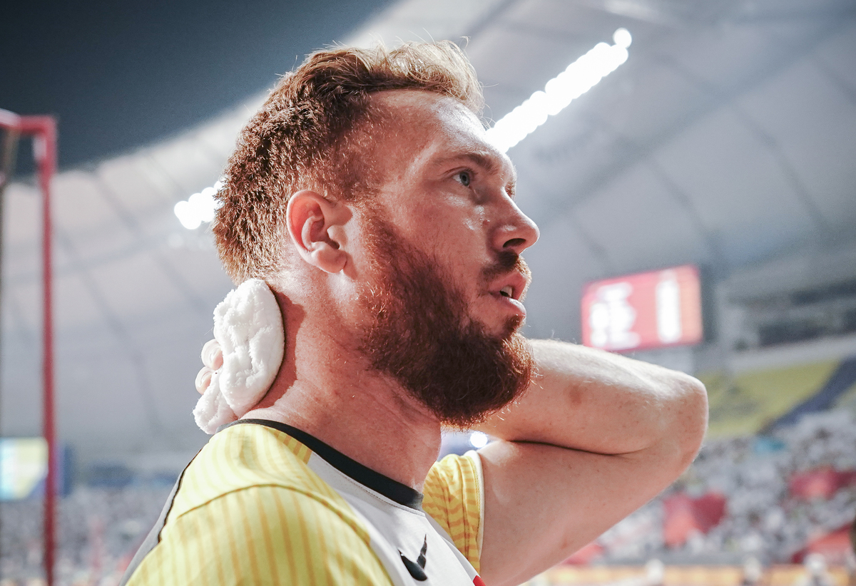 An athlete wipes the back of his neck with a washcloth.